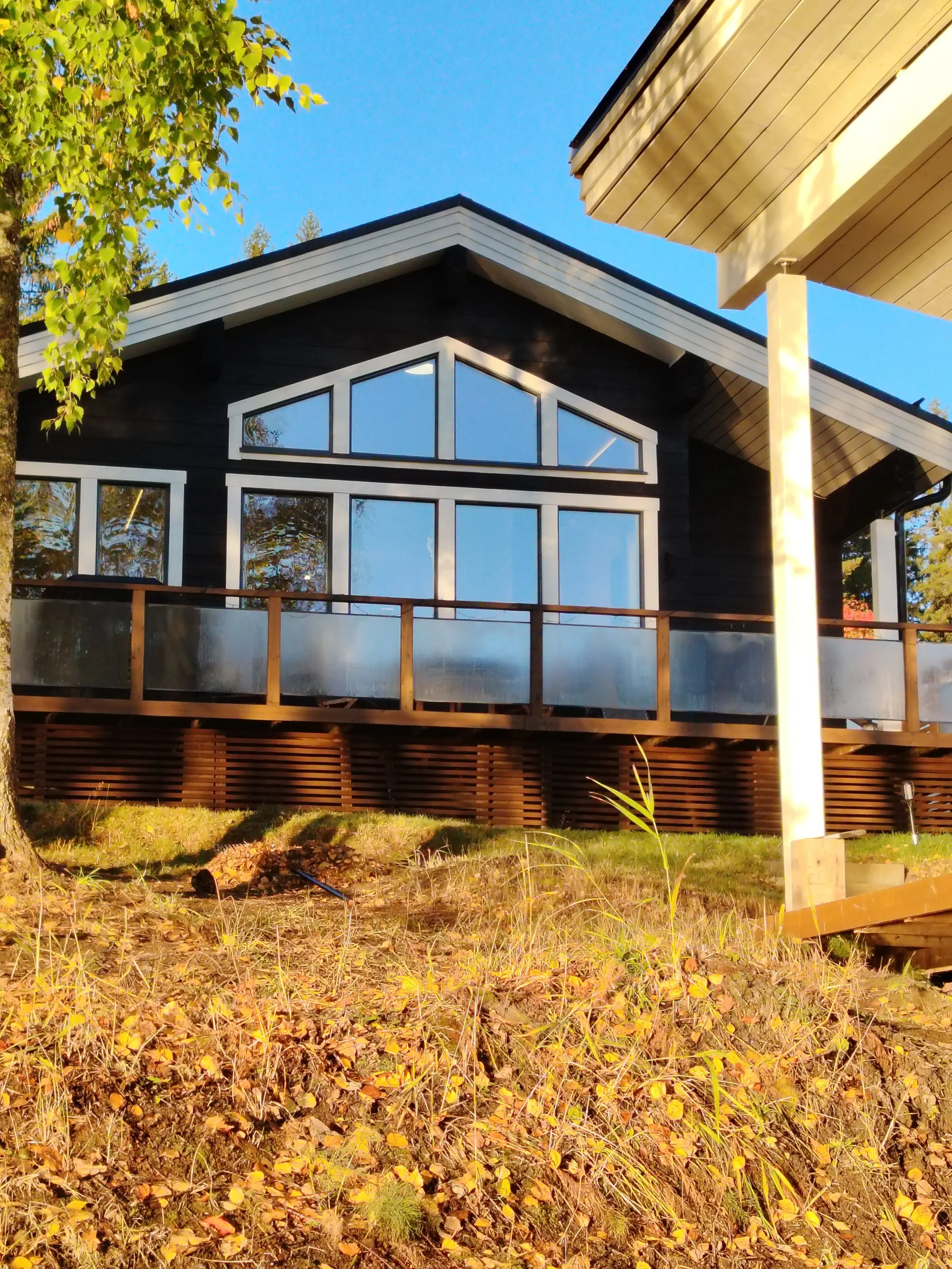 The dark log Villa's lake-facing gable, with tall windows above the terrace.