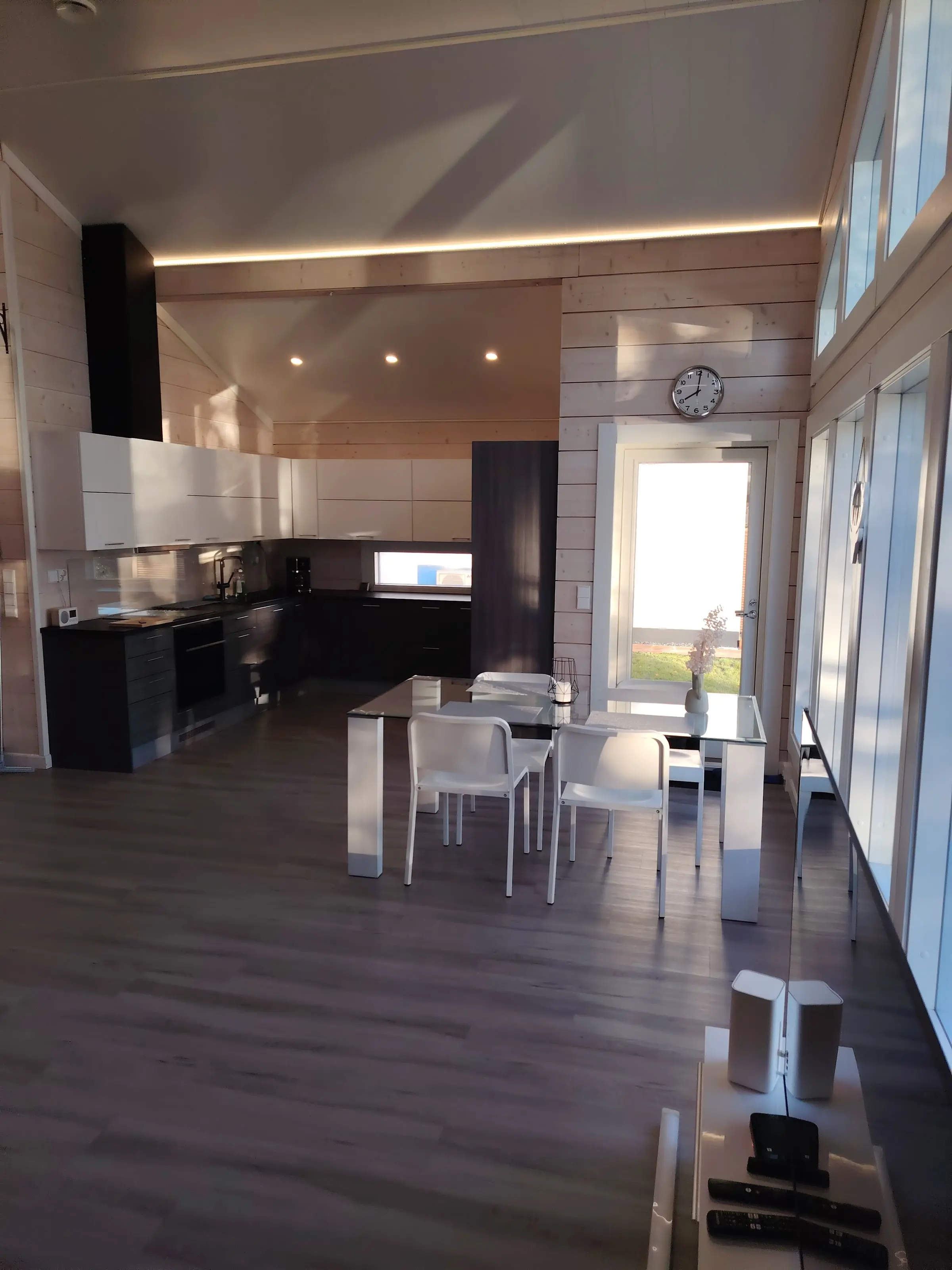 The kitchen with white upper and dark lower cabinets, and a glass dining table with white chairs.