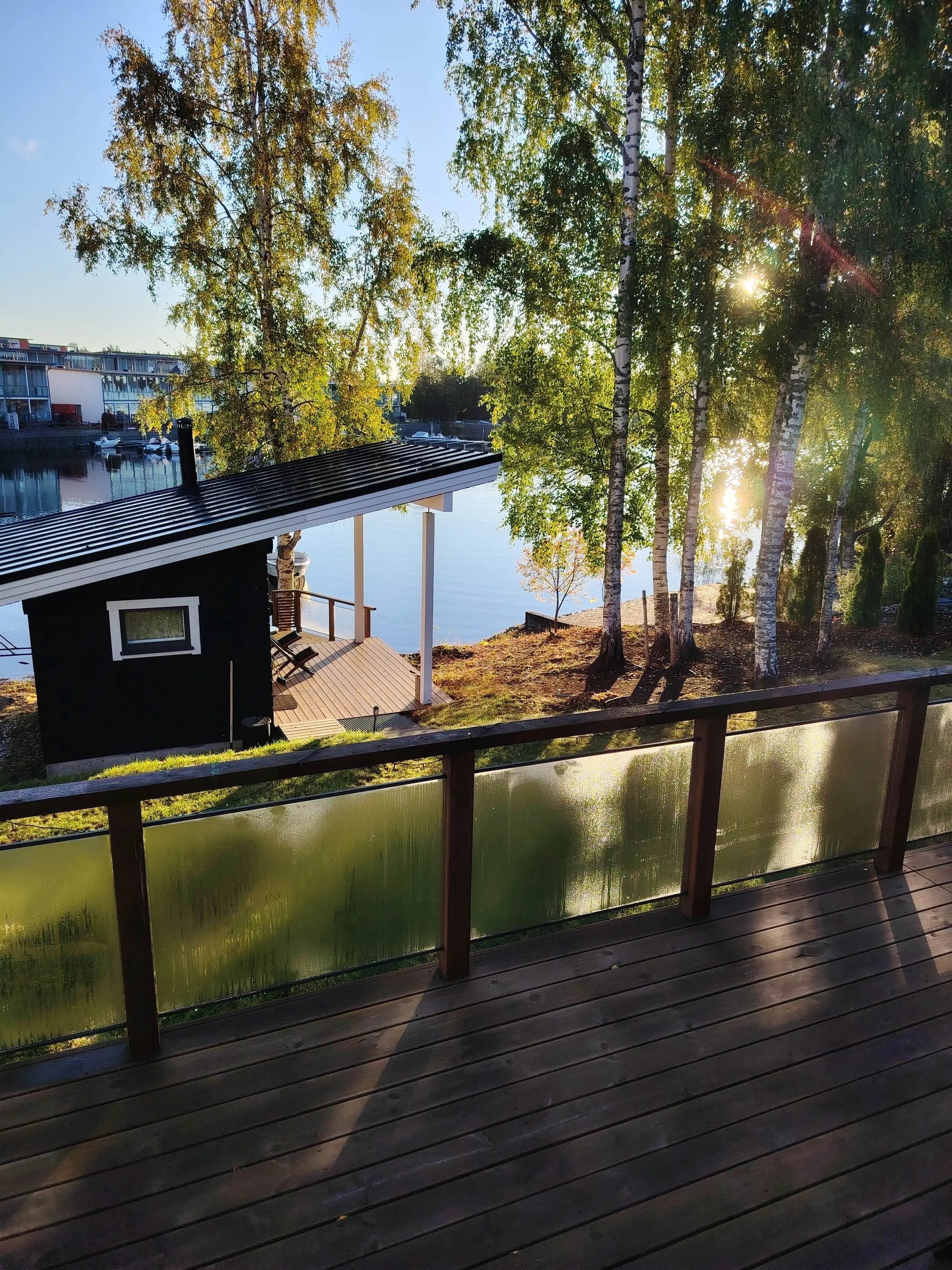 View from the Villa terrace down to Rantasauna and the lake, with morning sun through the birches.